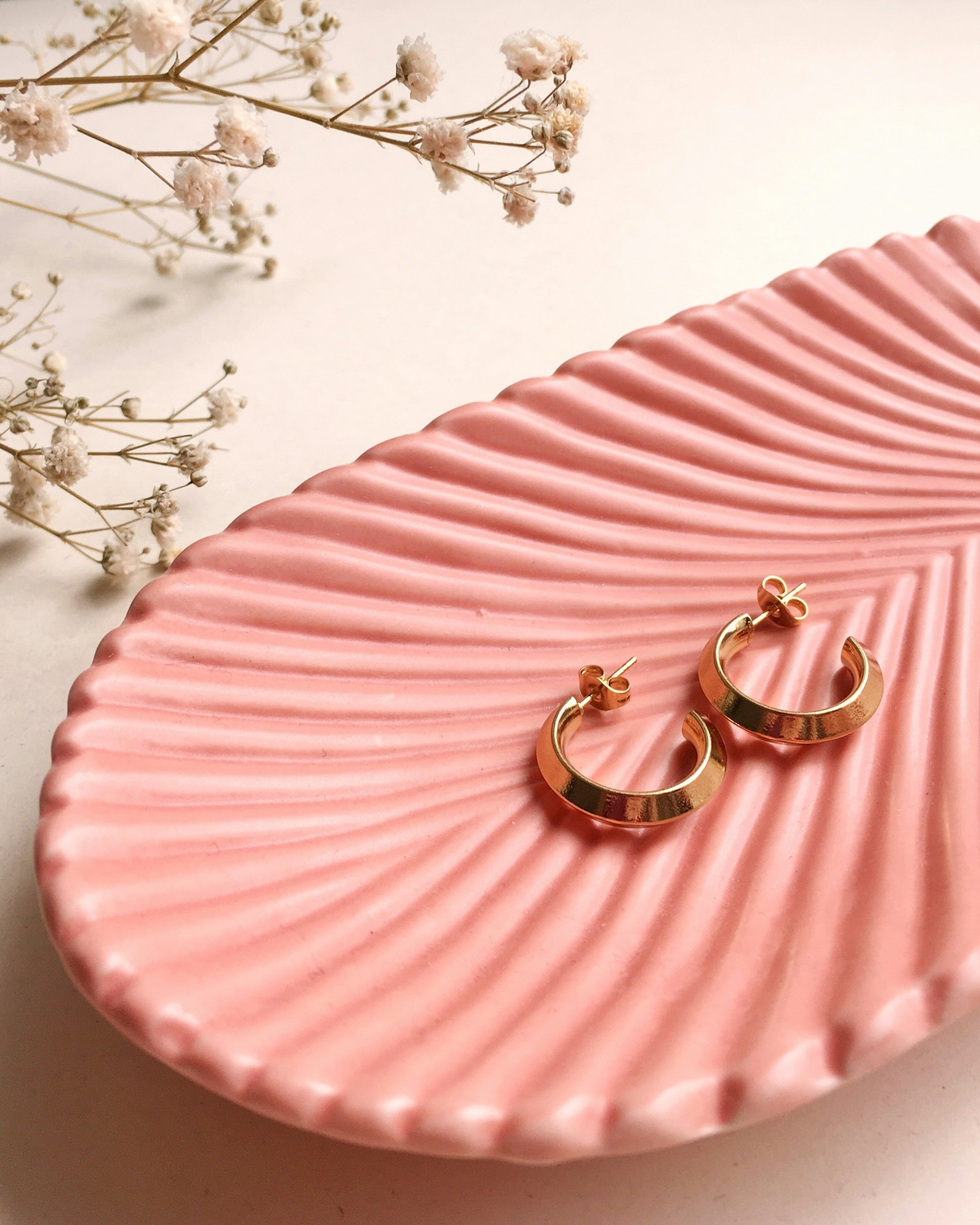 Hoop earrings on a pink jewellery dish, a gift idea for her
